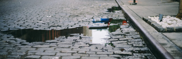 Cobble stone street with puddles and pot holes; Essex County Slip and Fall Attorneys concept image