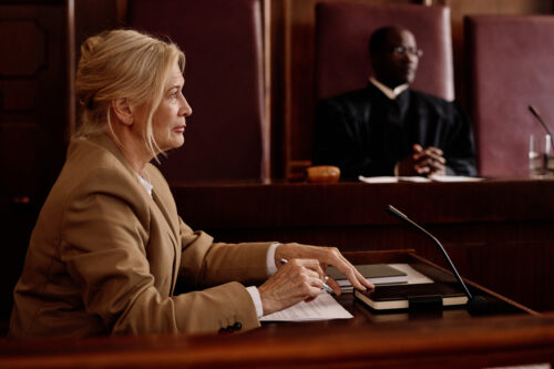 Side view of mature blond female witness or lawyer speaking in microphone