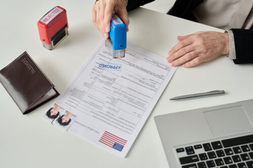 Close up of unrecognizable worker putting approved stamp on visa application form in US immigration office