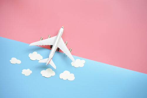 Flat lay design of travel concept with plane and cloud on blue and pink background with copy space.