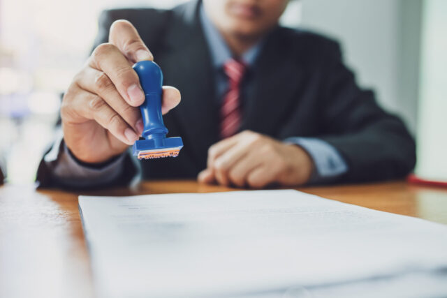 Businessman stamping with approved stamp on document contract.