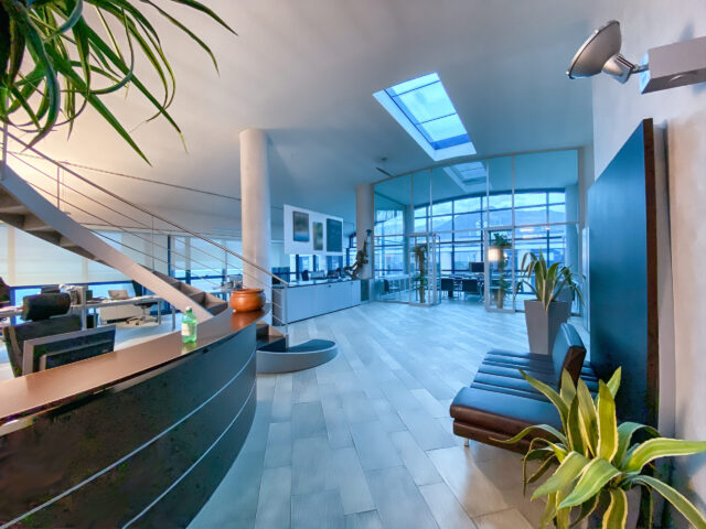 Side view of modern open space office interior with rows of computer tables with desktops standing on them.